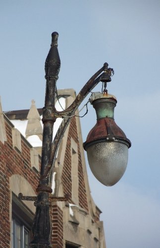 Old street lamp against a brick building, lit up like a dance floor
